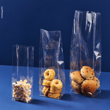 Sacchetto a fondo quadro, trasparente, ripieno di caramelle e dolci, aperti, varie misure. Sfondo blu